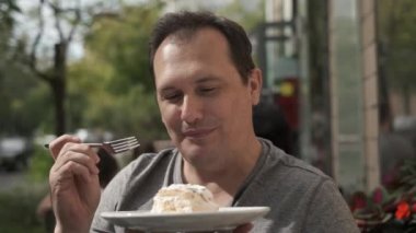 Adam kremalı pasta yiyor.