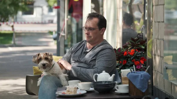 Man drinking tea with small jack russell dog lying in his lap