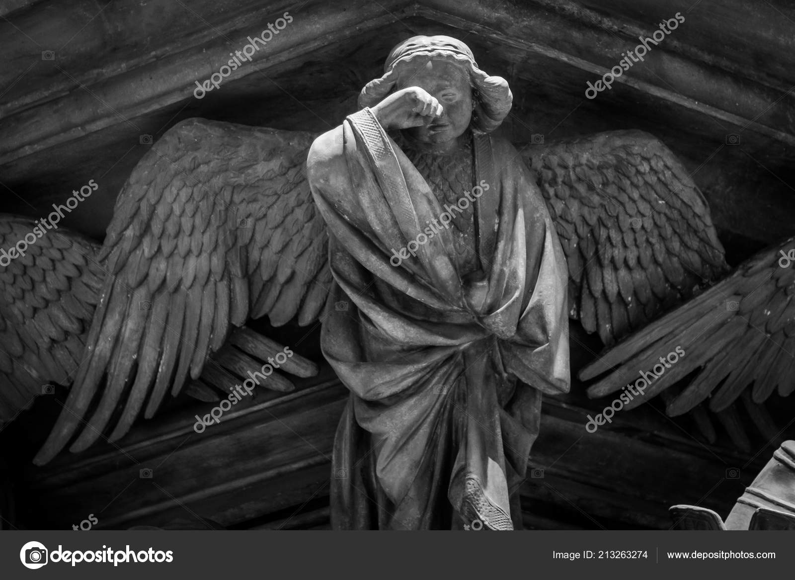 Ancient sculpture of a crying angel of concrete Stock Photo by