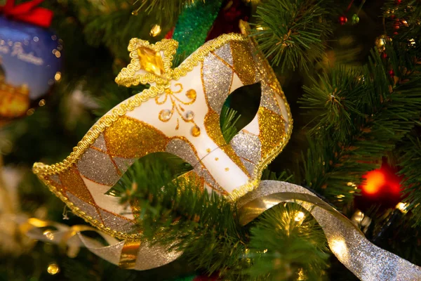 Hermosa máscara de carnaval colgando en el árbol de Navidad en el fondo de decoraciones navideñas brillantes —  Fotos de Stock