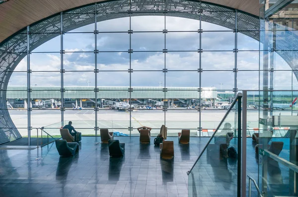 Paris, France, April 1, 2017: Looking out a large ellipsoid window at Charles De Gaulle airport with two rows of chairs in silhouette in front of it — Stock Photo, Image