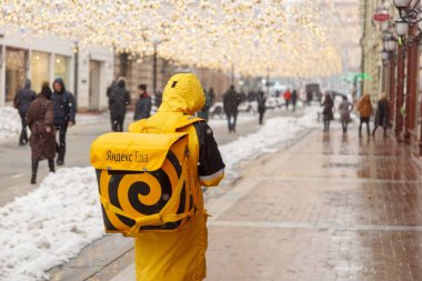 MOSCOW, RUSSIA - FEBRUARY 13,2019: A man from the delivery service of food - Yandex Eda, on the streets of city.food delivery clipart