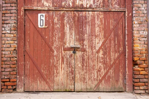 Porta de garagem velha em uma parede de concreto branco. Portões feitos de madeira pintada com tinta verde rachada — Fotografia de Stock