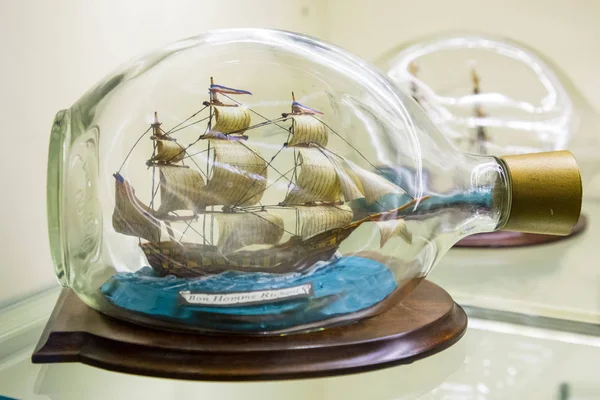 Istanbul, Turkey, March 2019: Miniature tall ship with sails rigged in a clear glass bottle displayed on a small wooden stand over a white background, nautical theme. Rahmi M. Koc Industrial Museum — Stock Photo, Image