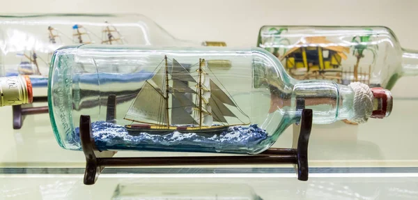 Istanbul, Turkey, March 2019: Miniature tall ship with sails rigged in a clear glass bottle displayed on a small wooden stand over a white background, nautical theme. Rahmi M. Koc Industrial Museum — Stock Photo, Image