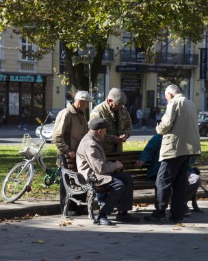 Lviv / Ukrayna - 06 Ekim 2018: büyük erkek sonbahar gününde bankların üzerinde oturan bir grup. Lviv, Ukrayna Svobody Ave.