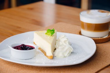 Tabakta meyve ve kapuçino olan bir dilim cheesecake. Metin için boşluk