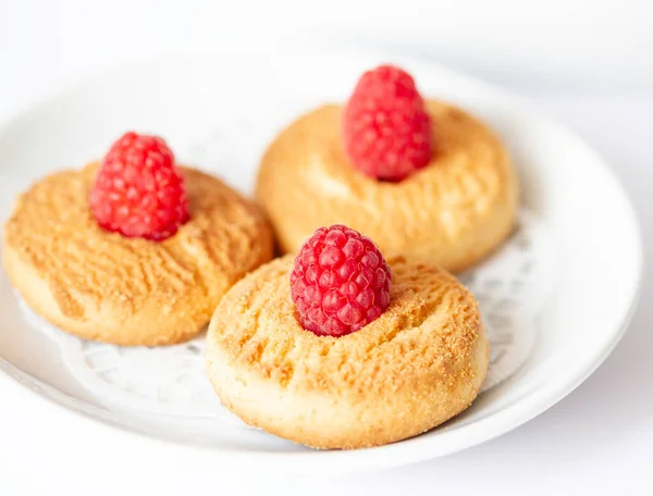 Cookies with a raspberry on the white plate