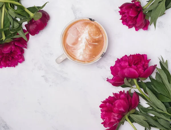 Fincan kapuçino ve pembe peonies mermer zemin üzerine,