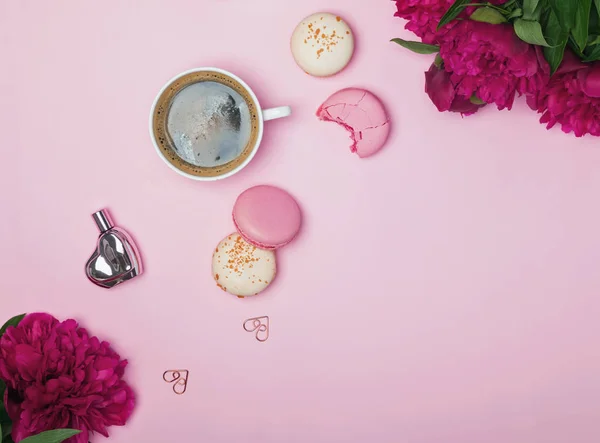 Rosa Pfingstrosen, Kaffee und französische Macarons auf pastellrosa Hintergrund — Stockfoto