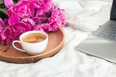 Kahve, peonies ve yatağın üstünde laptop