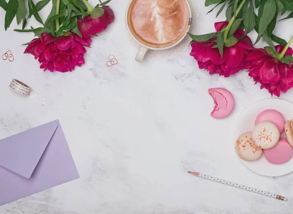 Coffee, pink peonies and macarons on the marble background — Stock Photo, Image