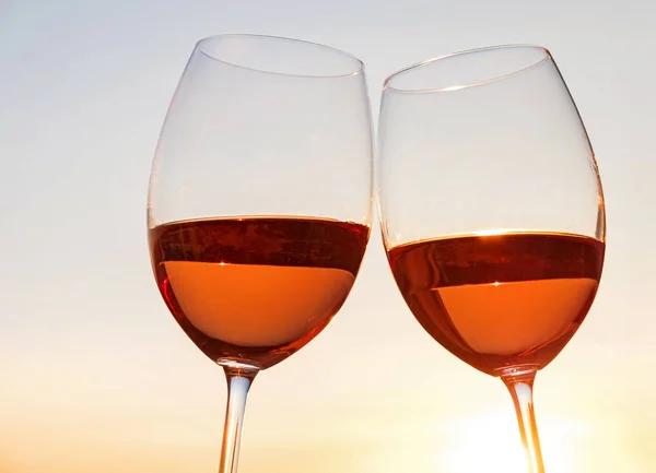 Two wine glasses on the sky background at sunset light. — Stock Photo, Image