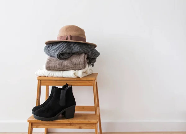 Lot de pulls, bonnets et bottes tricotés près du mur blanc . — Photo