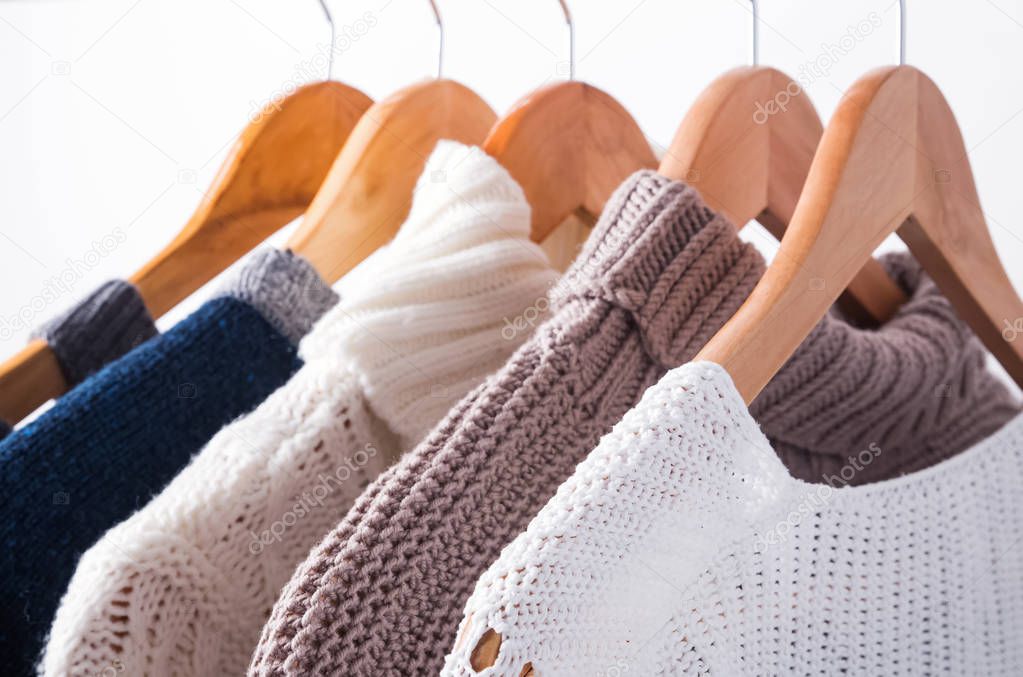 Knitted sweaters on hangers close-up