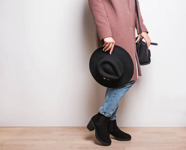 Woman in beige coat and stylish boots holding a hat in hand. — Stock Photo, Image