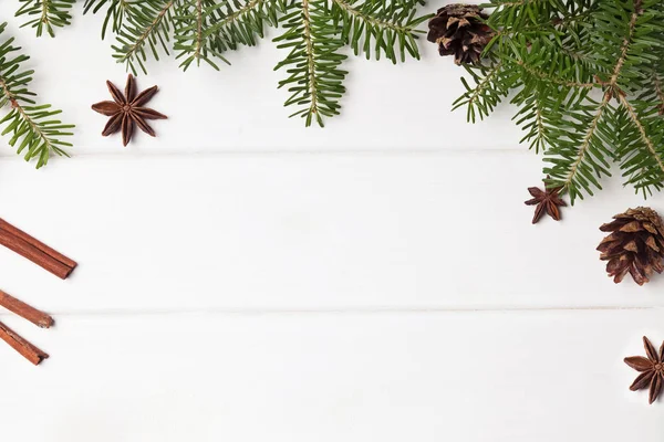 Fenyő ágak és a fehér fa háttér karácsonyi fűszerek — Stock Fotó