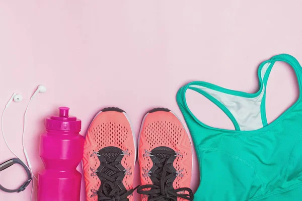 Feminine fitness accessories: sneakers, bottle with water and sports bra