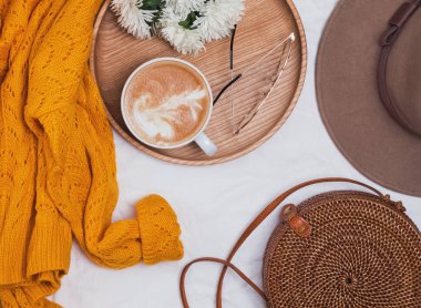 Kadınsı aksesuarları ile düz yatıyordu: kazak, şapka, çanta ve gözlük.