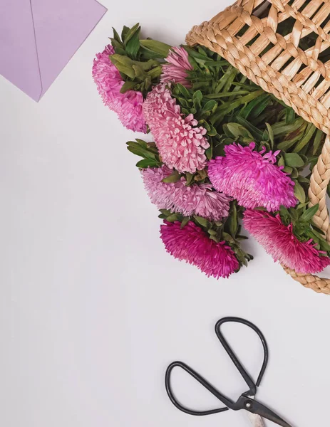 Roze bloemen in een stro mand op de witte achtergrond — Stockfoto