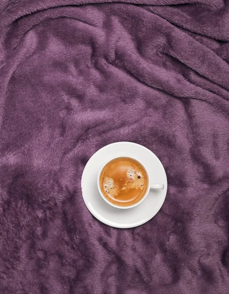 Cup of coffee on the bed with purple plaid or blanket, top view — Stock Photo, Image