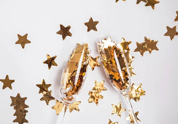 Gouden confetti in champagneglazen op de witte achtergrond. — Stockfoto