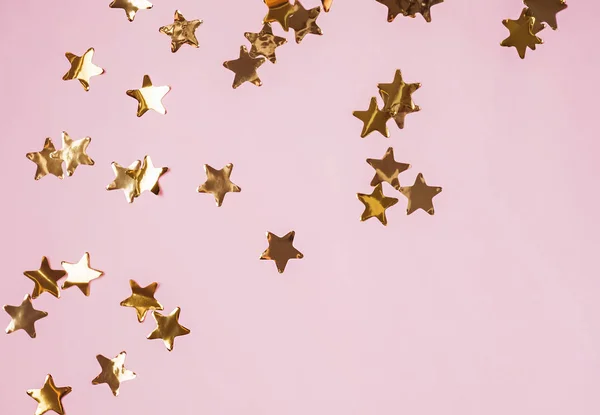 Golden shiny decorative stars on the pink background, top view. — Stock Photo, Image