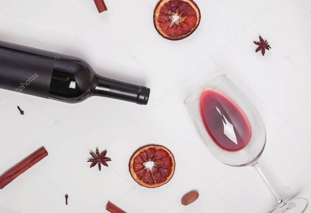 Bottle of wine, glass with poured wine and dry spices on the white background