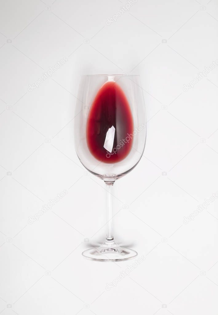 Glass with poured red wine lying on the white background