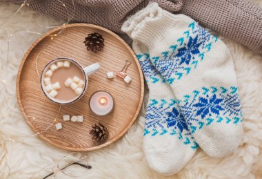 Soğuk hava aksesuarları, rahat çorap, sıcak kakao marshmallows ve yanan mum, üstten görünüm.