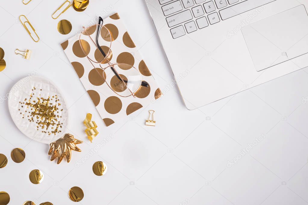 Laptop and golden color decor on the white table