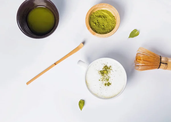 Matcha Latte in einer Tasse, Puder und Werkzeuge zur Teezubereitung auf weißem Hintergrund, — Stockfoto
