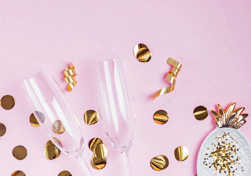 Party decor of golden color and champagne glasses on the pink background