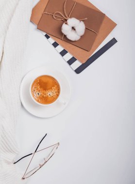 Kahve, gözlük ve beyaz masanın üzerine not defterleri.