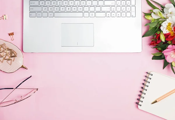 Laptop, flores e outros acessórios sobre o fundo rosa — Fotografia de Stock