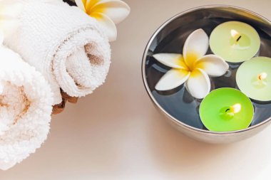 Rulo havlu, mumlar ve frangipani çiçekler.