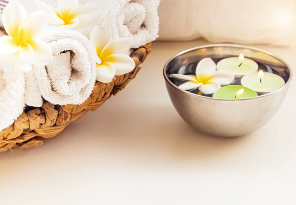 Раскатанные полотенца, свечи и цветы франджипани
.