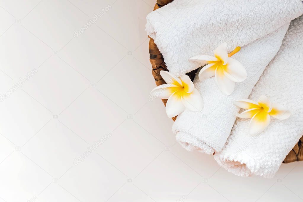 Clean rolled towels an plumeria flowers on the white table.