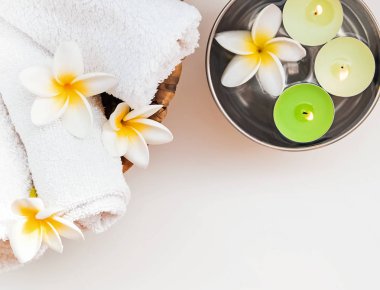 Rulo havlu, mumlar ve frangipani çiçekler.
