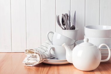 Ayakta beyaz ahşap duvar yakınındaki farklı sofra, tabaklar, bardaklar