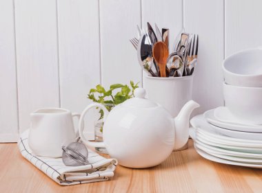 Ayakta beyaz ahşap duvar yakınındaki farklı sofra, tabaklar, bardaklar