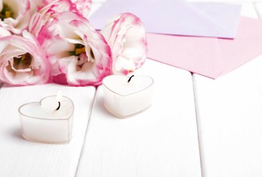 Yanan mumlar ve beyaz zemin üzerine güzel çiçekler iki kalp şeklinde