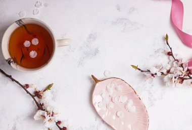 Bahar çiçek açan şube ve beyaz yaprakları ile mermer tabloda çay