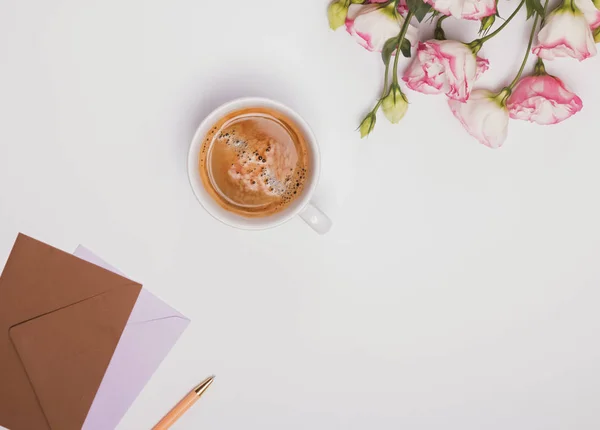 Kaffe, blommor och kuvert på vita. — Stockfoto