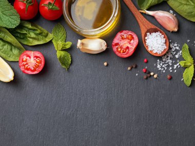 Fesleğen, zeytinyağı, tuz ve diğer malzemeler siyah taş zemin üzerine