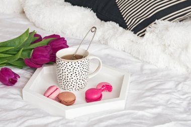 Bir fincan çay ve macarons tepsi ayakta beyaz yatak yakın çekim ile yatağa üzerinde