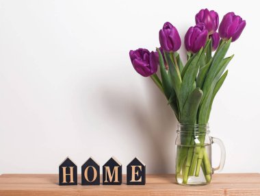 Thewall oturma odasında yakın duran bir cam kavanoza mor laleler