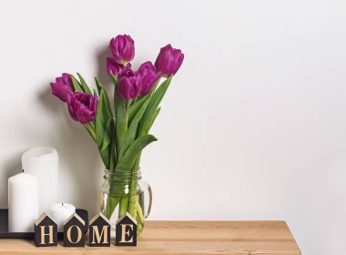 Thewall oturma odasında yakın duran bir cam kavanoza mor laleler