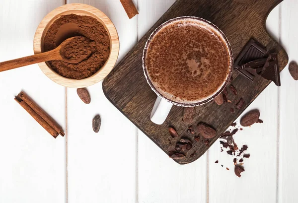 Hot chocolate in the cup, cocoa beans and powder on the white wooden table — Stock Photo, Image