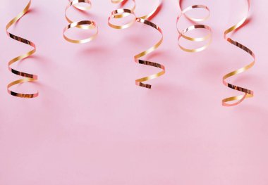 Pastel pembe arka plan üzerinde izole altın kıvırcık şeritler.